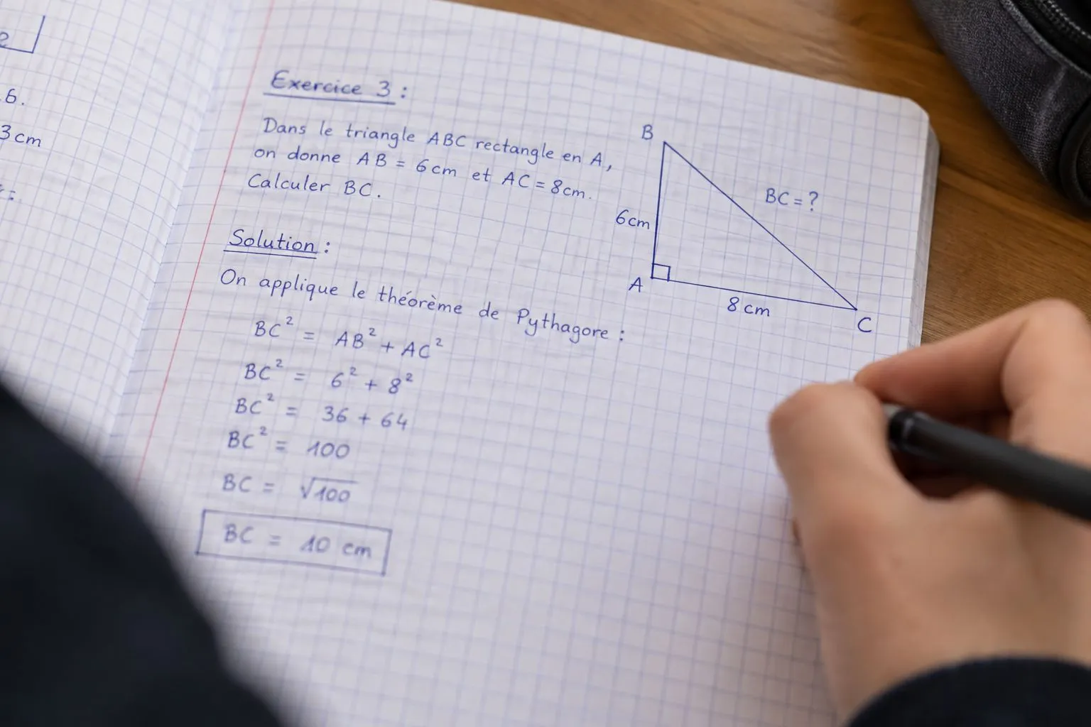Cahier d’élève avec un exercice résolu sur le théorème de Pythagore : triangle rectangle et calcul de BC = 10 cm